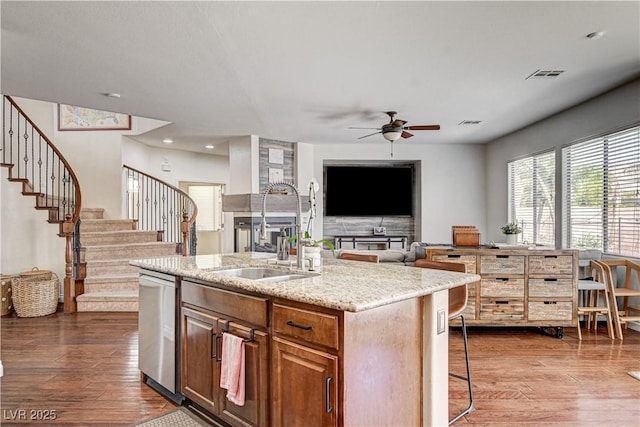 1717 Jake Andrew Ave, North Las Vegas, NV 89086 - kitchen featuring stainless steel dishwasher, dark wood finished floors, a ceiling fan, an island with sink, and light stone countertops
