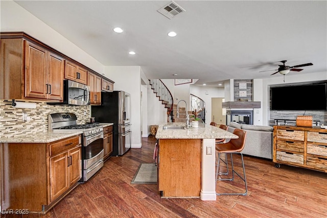 1717 Jake Andrew Ave, North Las Vegas, NV 89086 - kitchen with stainless steel appliances, light stone countertops, a breakfast bar area, ceiling fan, and decorative backsplash