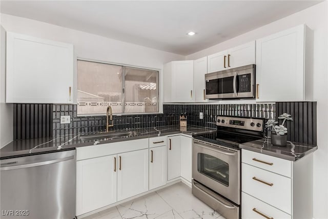 3826 Edmond St, Las Vegas, NV 89103 - kitchen with appliances with stainless steel finishes, white cabinetry, light marble finish flooring, dark countertops, and backsplash