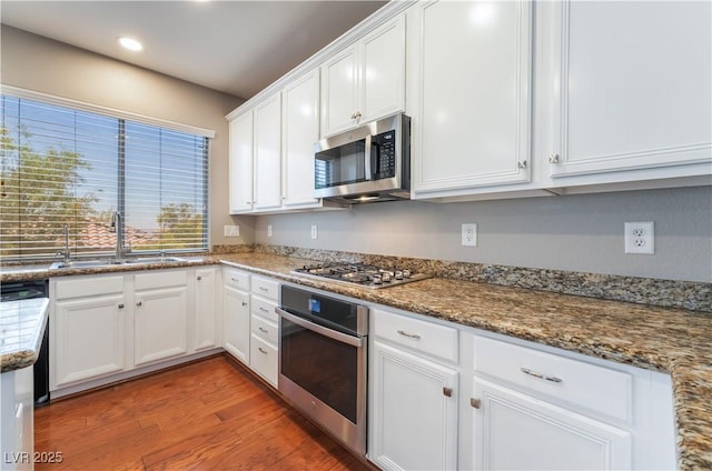 11901 Luna Del Mar Ln, Las Vegas, NV 89138 - kitchen featuring appliances with stainless steel finishes, white cabinetry, wood finished floors, stone counters, and recessed lighting