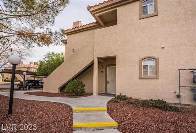 5415 W Harmon Ave Unit 1162, Las Vegas, NV 89103 - property entrance with stucco siding, a tile roof, and a chimney