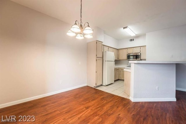 5415 W Harmon Ave Unit 1162, Las Vegas, NV 89103 - kitchen featuring stainless steel microwave, freestanding refrigerator, a chandelier, light countertops, and light wood-style flooring