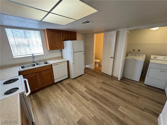 453 Las Casitas Way, Las Vegas, NV 89121 - kitchen featuring white appliances, light wood-style flooring, washer and dryer, brown cabinets, and a textured ceiling