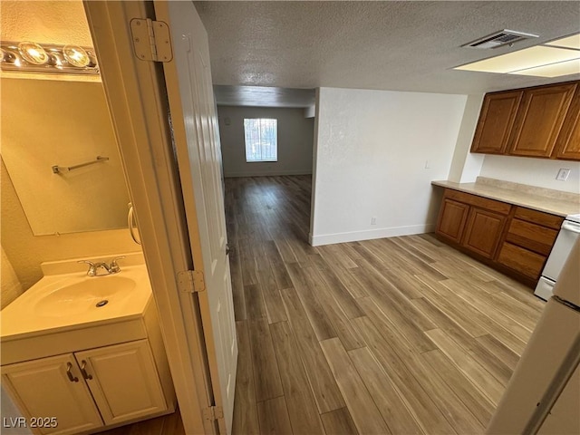 453 Las Casitas Way, Las Vegas, NV 89121 - kitchen featuring a textured ceiling, light wood finished floors, light countertops, and brown cabinetry