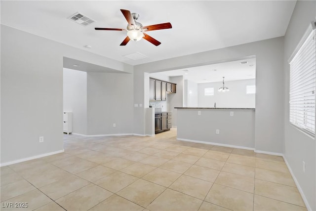 7263 Pepperbox Ave, Las Vegas, NV 89179 - unfurnished living room featuring ceiling fan, light tile patterned flooring, plenty of natural light, and a chandelier