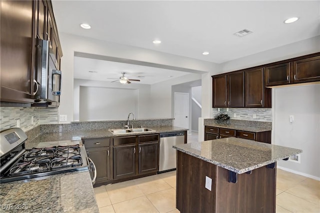 7263 Pepperbox Ave, Las Vegas, NV 89179 - kitchen featuring appliances with stainless steel finishes, light tile patterned flooring, dark brown cabinets, stone counters, and ceiling fan