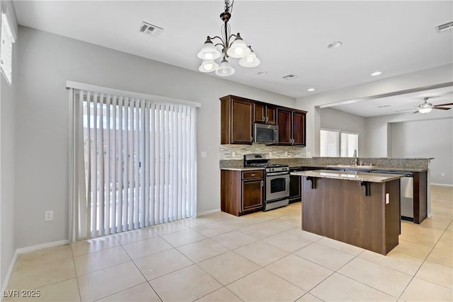 7263 Pepperbox Ave, Las Vegas, NV 89179 - kitchen with stainless steel appliances, a center island, dark brown cabinetry, a breakfast bar, and decorative backsplash