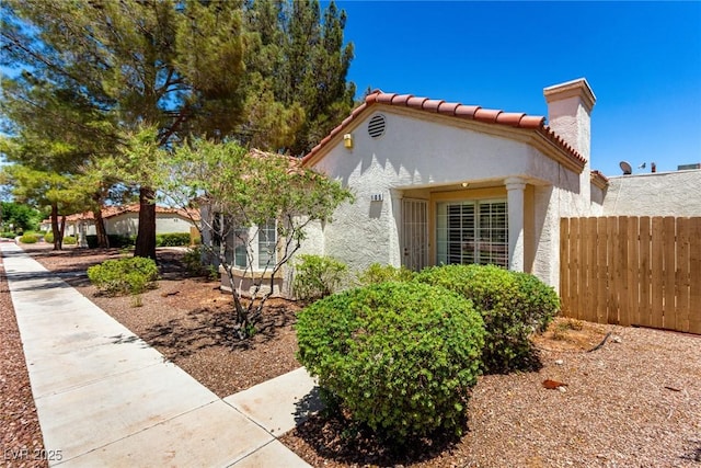 5424 Geneive Ln Unit 105, Las Vegas, NV 89108 - view of side of home with stucco siding, a tile roof, and a chimney