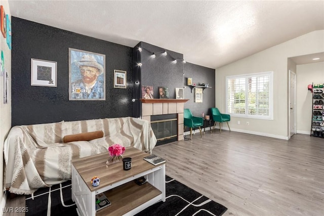5424 Geneive Ln Unit 105, Las Vegas, NV 89108 - living room with an accent wall, vaulted ceiling, wood finished floors, a tile fireplace, and a textured ceiling