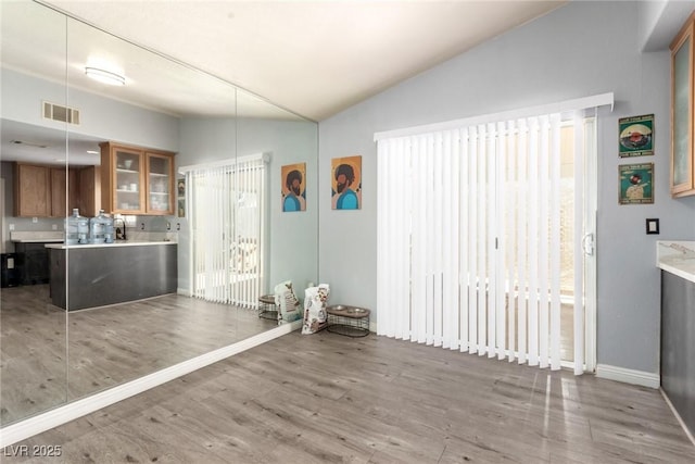 5424 Geneive Ln Unit 105, Las Vegas, NV 89108 - kitchen with lofted ceiling, brown cabinets, light countertops, wood finished floors, and glass insert cabinets