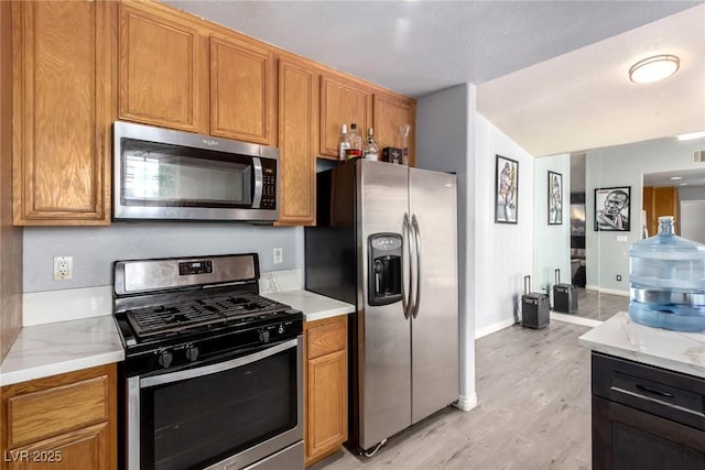 5424 Geneive Ln Unit 105, Las Vegas, NV 89108 - kitchen featuring appliances with stainless steel finishes, light wood finished floors, brown cabinets, and light stone counters