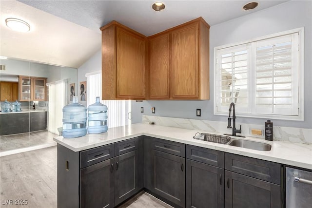 5424 Geneive Ln Unit 105, Las Vegas, NV 89108 - kitchen featuring dishwasher, lofted ceiling, light wood-type flooring, a peninsula, and light stone countertops