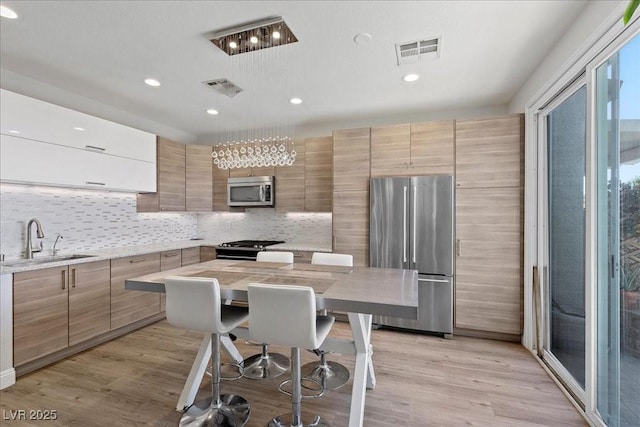 694 Value Ridge Ave, Henderson, NV 89012 - kitchen with appliances with stainless steel finishes, tasteful backsplash, light wood-type flooring, modern cabinets, and recessed lighting