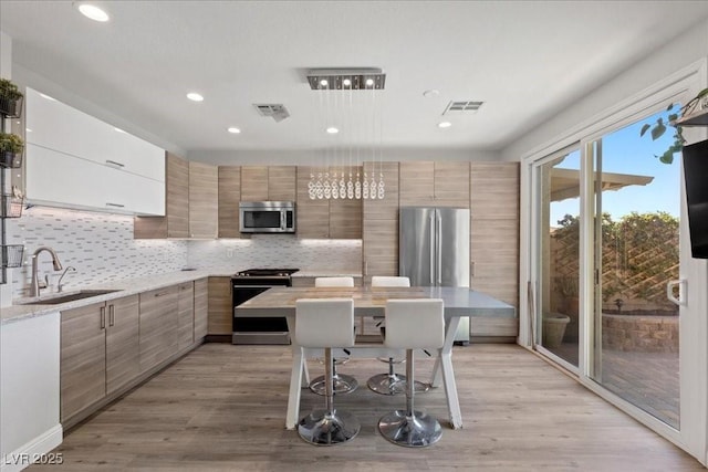 694 Value Ridge Ave, Henderson, NV 89012 - kitchen with stainless steel microwave, gas range, modern cabinets, decorative backsplash, and recessed lighting