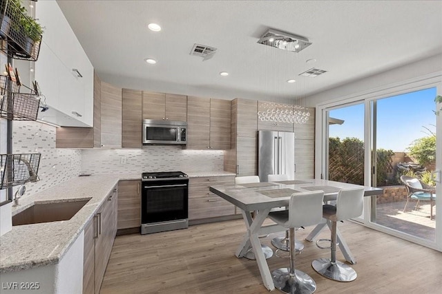 694 Value Ridge Ave, Henderson, NV 89012 - kitchen featuring appliances with stainless steel finishes, backsplash, recessed lighting, light wood finished floors, and modern cabinets
