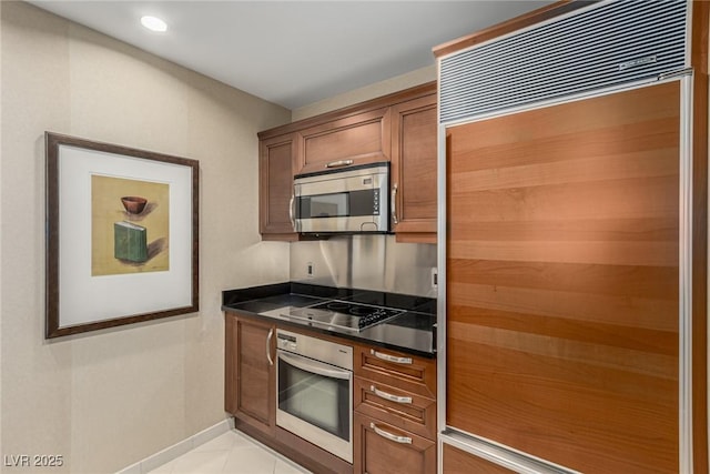 135 E Harmon Ave Unit 2702, Las Vegas, NV 89109 - kitchen featuring appliances with stainless steel finishes, dark countertops, light tile patterned floors, brown cabinetry, and recessed lighting