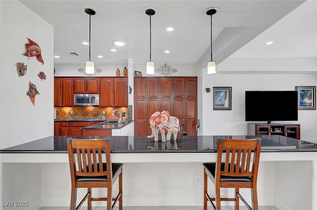 2779 Kindeace Ave, Henderson, NV 89044 - kitchen with stainless steel microwave, dark countertops, backsplash, a breakfast bar, and a large island