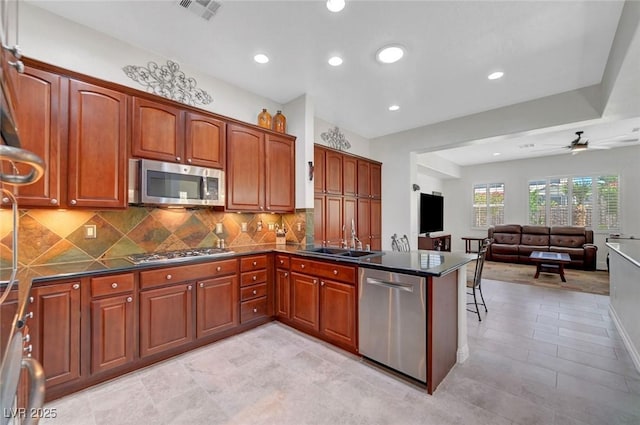 2779 Kindeace Ave, Henderson, NV 89044 - kitchen with stainless steel appliances, a peninsula, dark countertops, backsplash, and recessed lighting