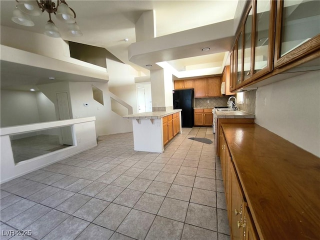 9693 Bighorn Island Ave, Las Vegas, NV 89148 - kitchen with freestanding refrigerator, tile countertops, light tile patterned floors, backsplash, and glass insert cabinets