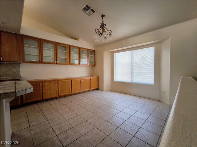 9693 Bighorn Island Ave, Las Vegas, NV 89148 - unfurnished dining area with light tile patterned floors, vaulted ceiling, and a chandelier