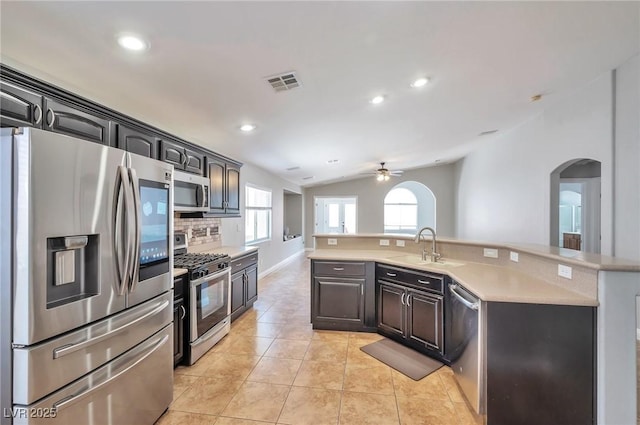 5732 Hornbrook St, North Las Vegas, NV 89031 - kitchen featuring appliances with stainless steel finishes, arched walkways, light countertops, a ceiling fan, and vaulted ceiling