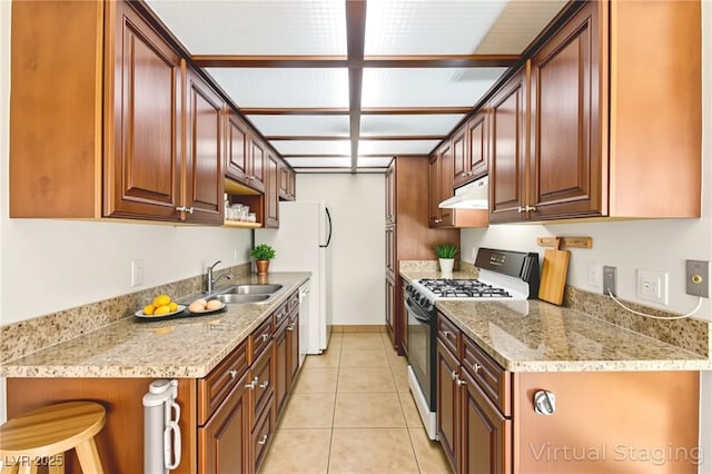 3668 Villa Knolls E Dr, Las Vegas, NV 89120 - kitchen featuring gas range oven, under cabinet range hood, light tile patterned floors, light stone countertops, and freestanding refrigerator