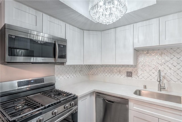 5219 Caliente St Unit 11, Las Vegas, NV 89119 - kitchen featuring appliances with stainless steel finishes, light countertops, white cabinetry, decorative backsplash, and a chandelier
