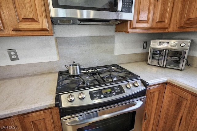 9357 Golden Timber Ln, Las Vegas, NV 89117 - kitchen with appliances with stainless steel finishes, light countertops, and brown cabinetry