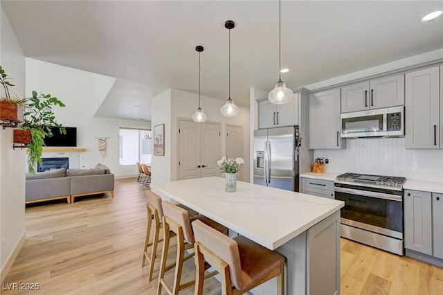 189 Andada Dr, Henderson, NV 89012 - kitchen with gray cabinetry, appliances with stainless steel finishes, light wood-type flooring, backsplash, and a kitchen island