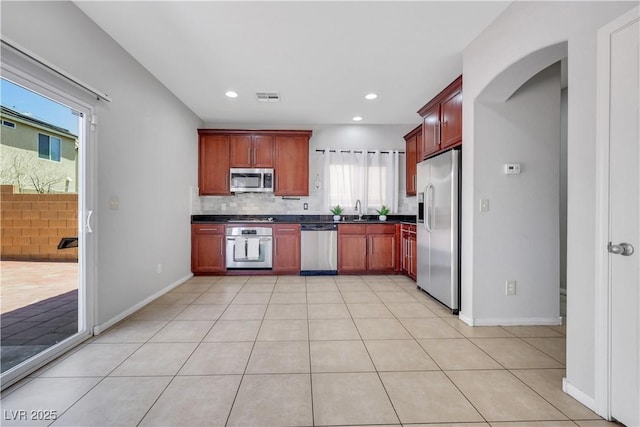 6678 Crystal Run Ln, Las Vegas, NV 89122 - kitchen featuring appliances with stainless steel finishes, dark countertops, reddish brown cabinets, backsplash, and recessed lighting