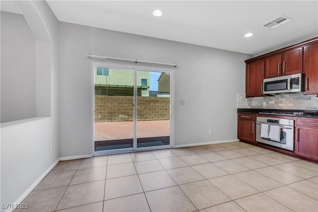 6678 Crystal Run Ln, Las Vegas, NV 89122 - kitchen with appliances with stainless steel finishes, dark countertops, tasteful backsplash, reddish brown cabinets, and arched walkways