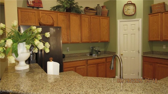1504 Andrew David Ave, North Las Vegas, NV 89086 - kitchen with freestanding refrigerator, brown cabinets, and light stone countertops