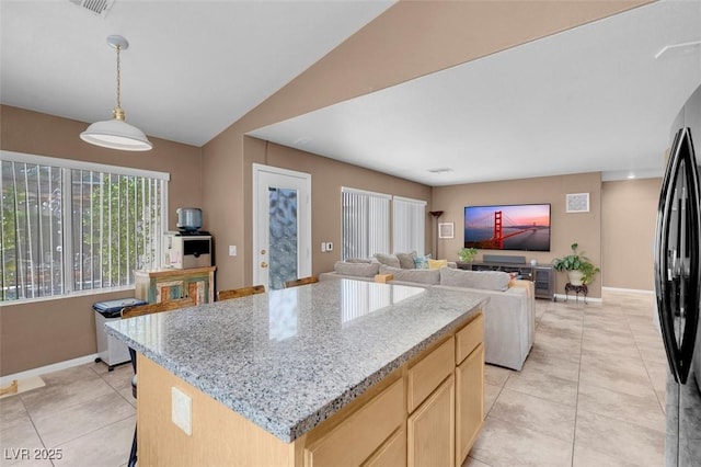 9909 Masked Duck Ave, Las Vegas, NV 89117 - kitchen with light brown cabinets, light tile patterned flooring, freestanding refrigerator, a kitchen island, and light stone counters