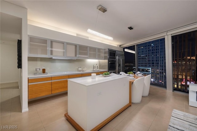 3722 Las Vegas Blvd Unit 2512E, Las Vegas, NV 89158 - kitchen featuring stainless steel appliances, light countertops, light tile patterned floors, glass insert cabinets, and a kitchen island
