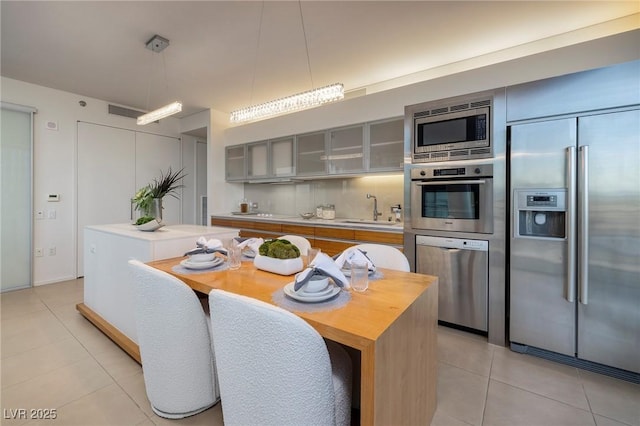 3722 Las Vegas Blvd Unit 2512E, Las Vegas, NV 89158 - kitchen with built in appliances, light tile patterned floors, glass insert cabinets, pendant lighting, and a center island