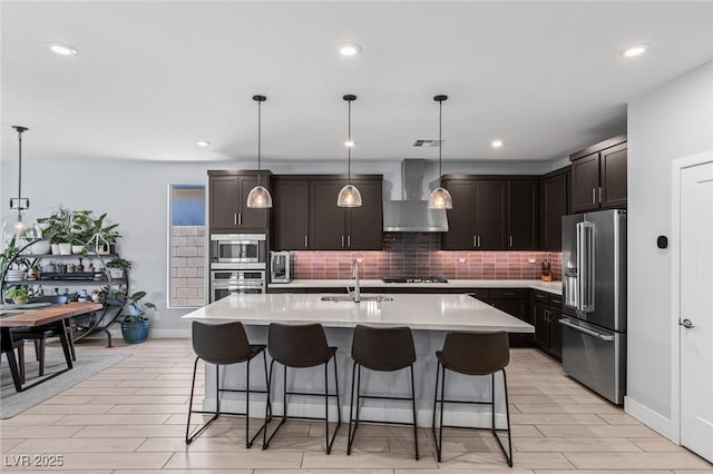 9785 Granite Mesa St, Las Vegas, NV 89141 - kitchen with stainless steel appliances, wall chimney exhaust hood, backsplash, a breakfast bar, and light countertops