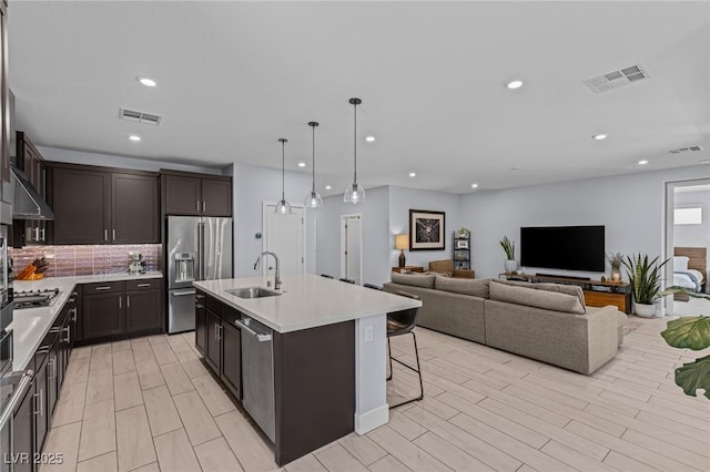 9785 Granite Mesa St, Las Vegas, NV 89141 - kitchen with stainless steel appliances, dark brown cabinetry, light countertops, tasteful backsplash, and a center island with sink