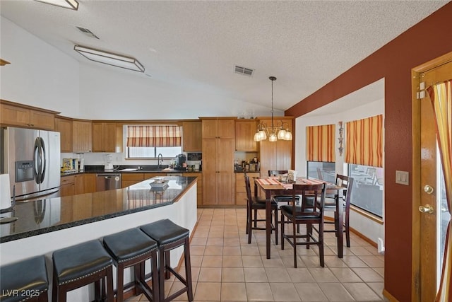 9100 Shelter Cove Ct, Las Vegas, NV 89117 - kitchen with appliances with stainless steel finishes, vaulted ceiling, a chandelier, a textured ceiling, and hanging light fixtures