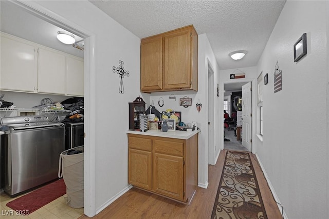 9100 Shelter Cove Ct, Las Vegas, NV 89117 - kitchen featuring independent washer and dryer, light wood-style flooring, a textured ceiling, and light countertops