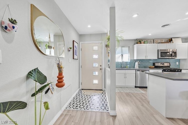 105 Shadow Ln, Las Vegas, NV 89106 - kitchen with stainless steel appliances, white cabinets, tasteful backsplash, light wood-style flooring, and recessed lighting