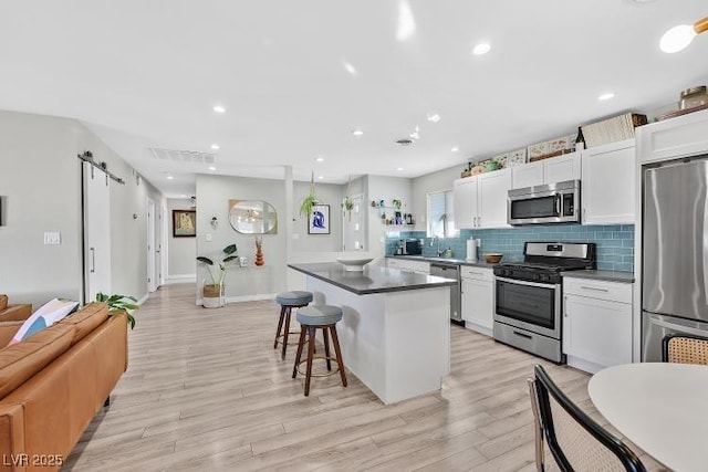 105 Shadow Ln, Las Vegas, NV 89106 - kitchen with stainless steel appliances, a breakfast bar, a barn door, a center island, and light wood-style flooring