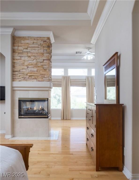 2041 Troon Dr, Henderson, NV 89074 - bedroom featuring ornamental molding, light wood-type flooring, a tray ceiling, and a multi sided fireplace