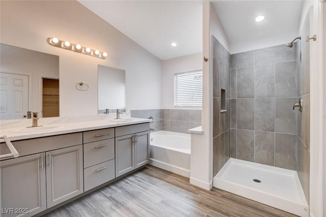 6346 Azurelyn Ave, Las Vegas, NV 89122 - bathroom featuring a bath, double vanity, a tile shower, wood finished floors, and vaulted ceiling
