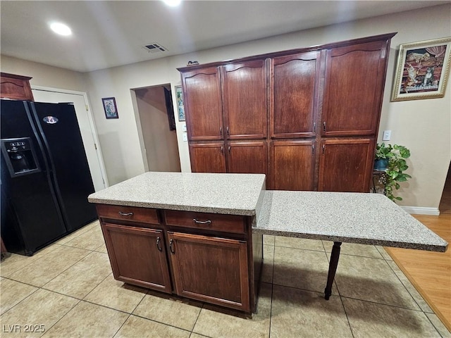 kitchen featuring black fridge, light countertops, light tile patterned floors, recessed lighting, and dark brown cabinets