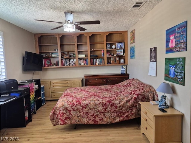 bedroom featuring light wood-style floors, a textured ceiling, and ceiling fan