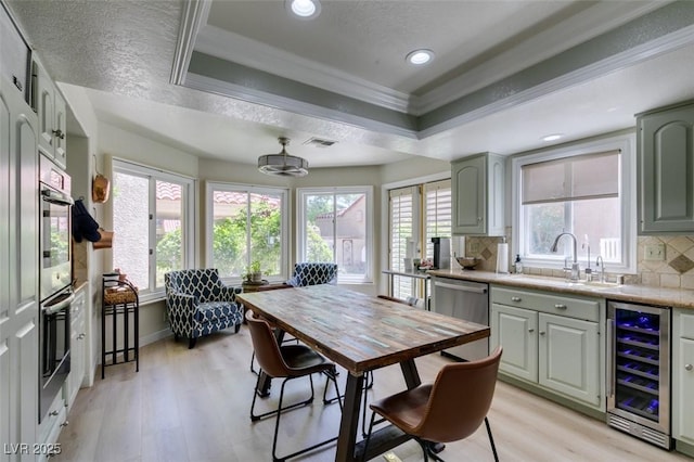 5133 Southern Hills Ln, Las Vegas, NV 89113 - dining area with beverage cooler, a tray ceiling, light wood finished floors, ornamental molding, and healthy amount of natural light