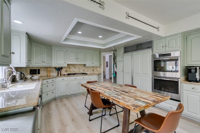 5133 Southern Hills Ln, Las Vegas, NV 89113 - kitchen featuring appliances with stainless steel finishes, a tray ceiling, backsplash, ornamental molding, and light wood-style floors