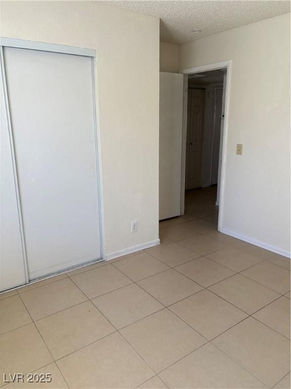925 Falconhead Ln Unit 102, Las Vegas, NV 89128 - unfurnished bedroom with a closet, light tile patterned floors, and a textured ceiling