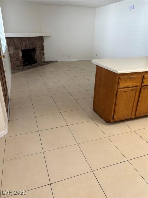 925 Falconhead Ln Unit 102, Las Vegas, NV 89128 - kitchen with a fireplace, light countertops, light tile patterned flooring, and brown cabinetry