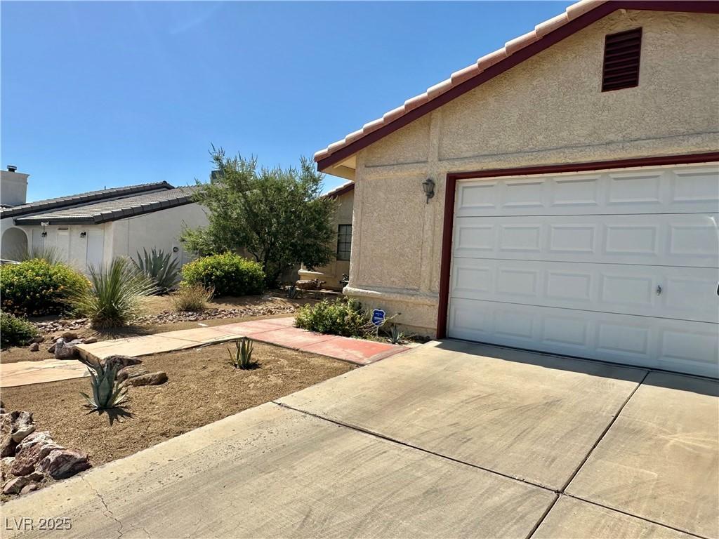 6357 Cobalt Ln, Las Vegas, NV 89146 - view of side of property with concrete driveway, stucco siding, an attached garage, and a tile roof
